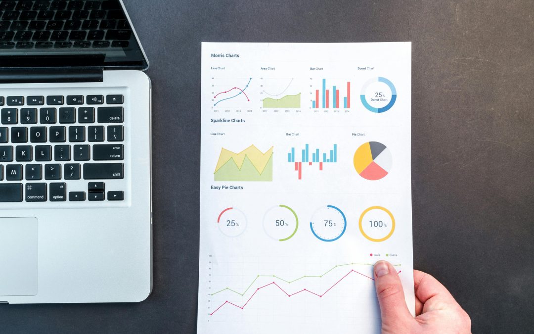 Detailed charts and graphs on a document next to a laptop, representing data analysis.